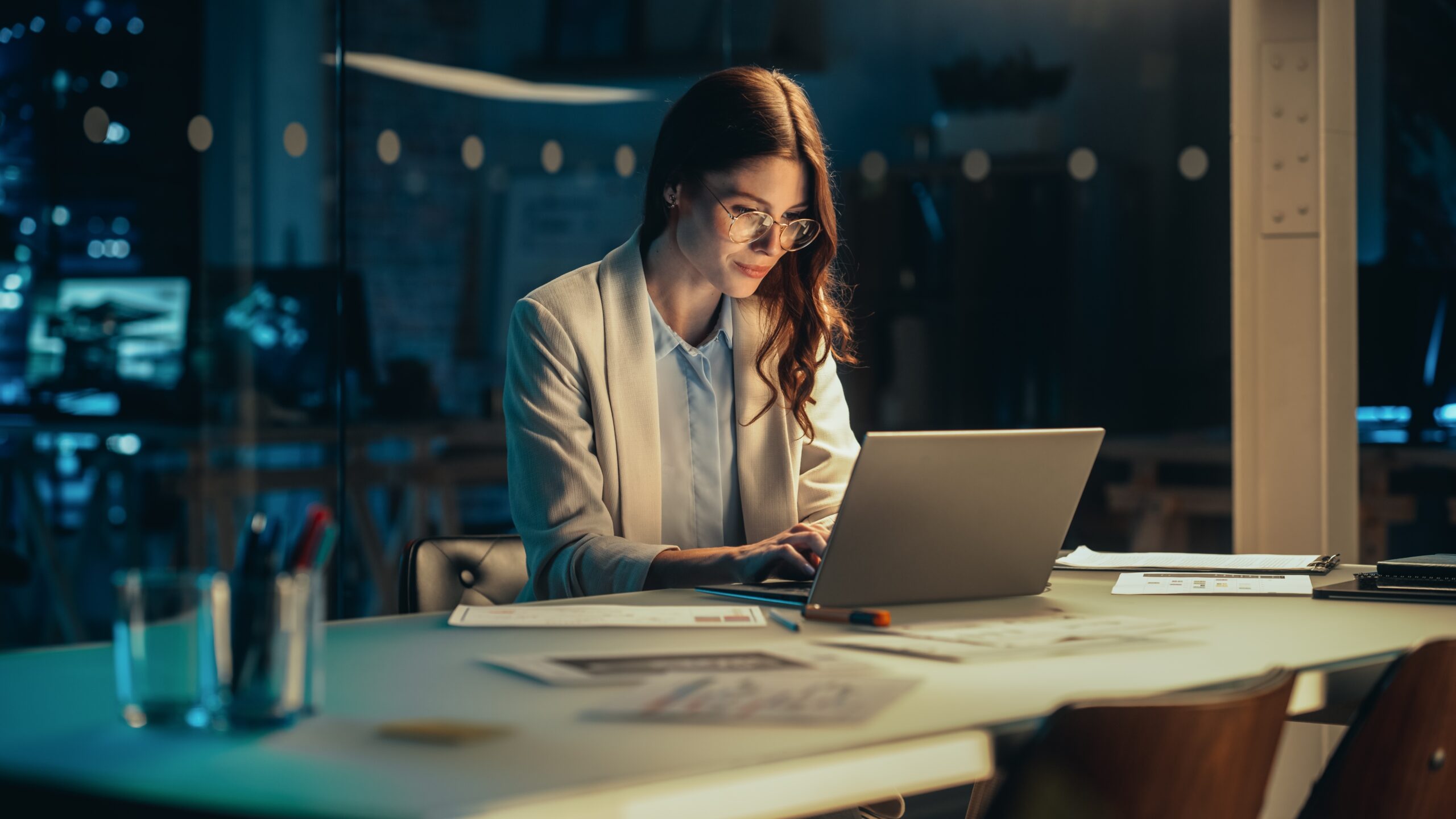 Woman sitting at a desk at night on her business laptop