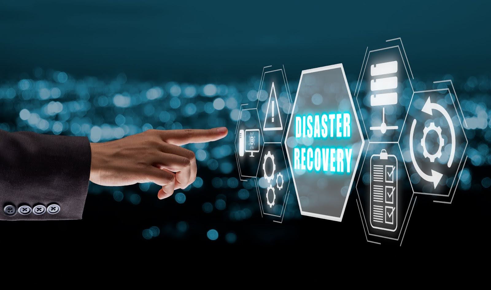 Hand reaching towards text on a screen that has graphics and says disaster recovery